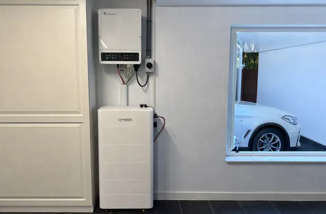 Thuisbatterij in een woning, naast een raam met een auto op de oprit