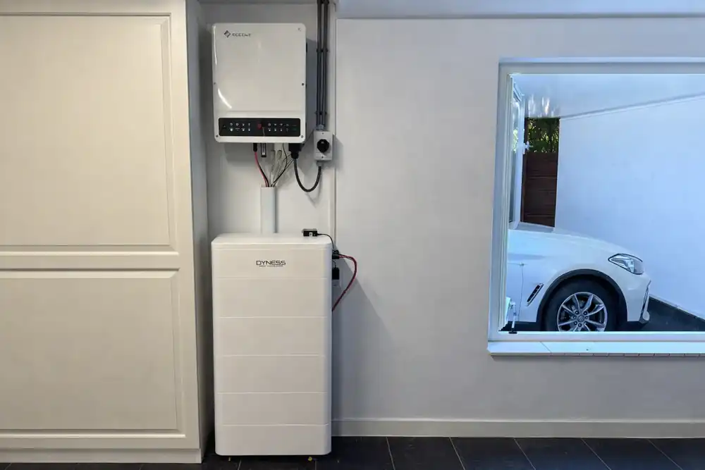 Thuisbatterij in een woning, naast een raam met een auto op de oprit